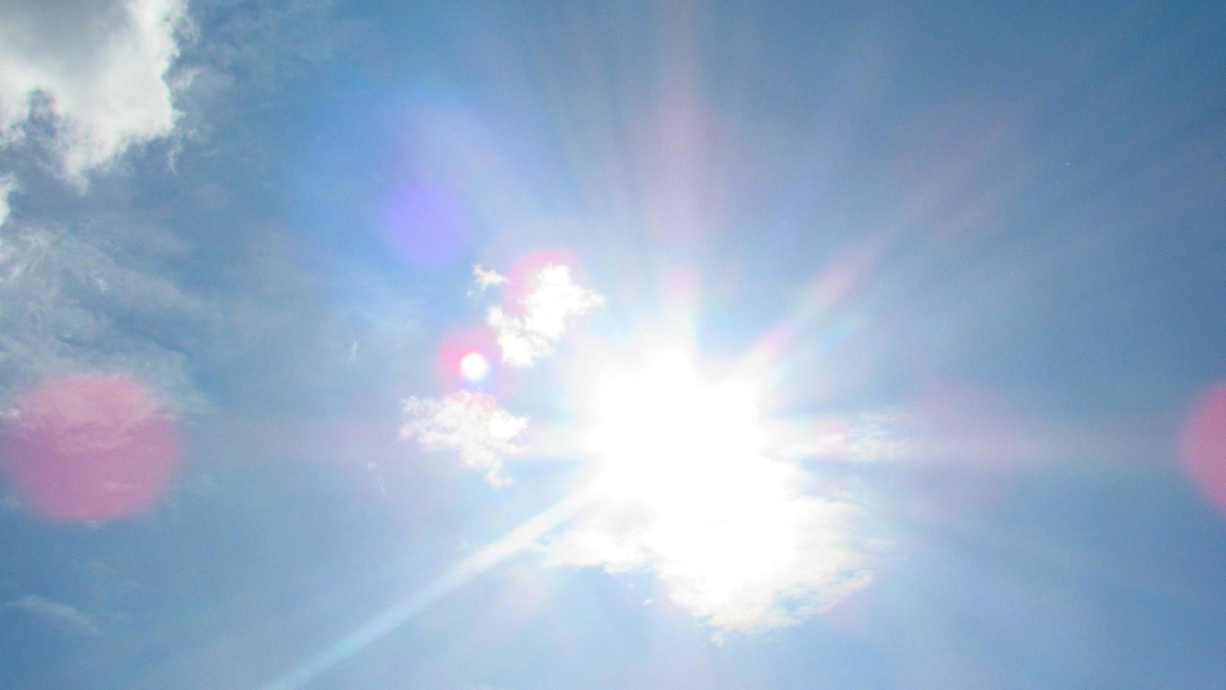 sun on the background of a blue sky with white clouds photo