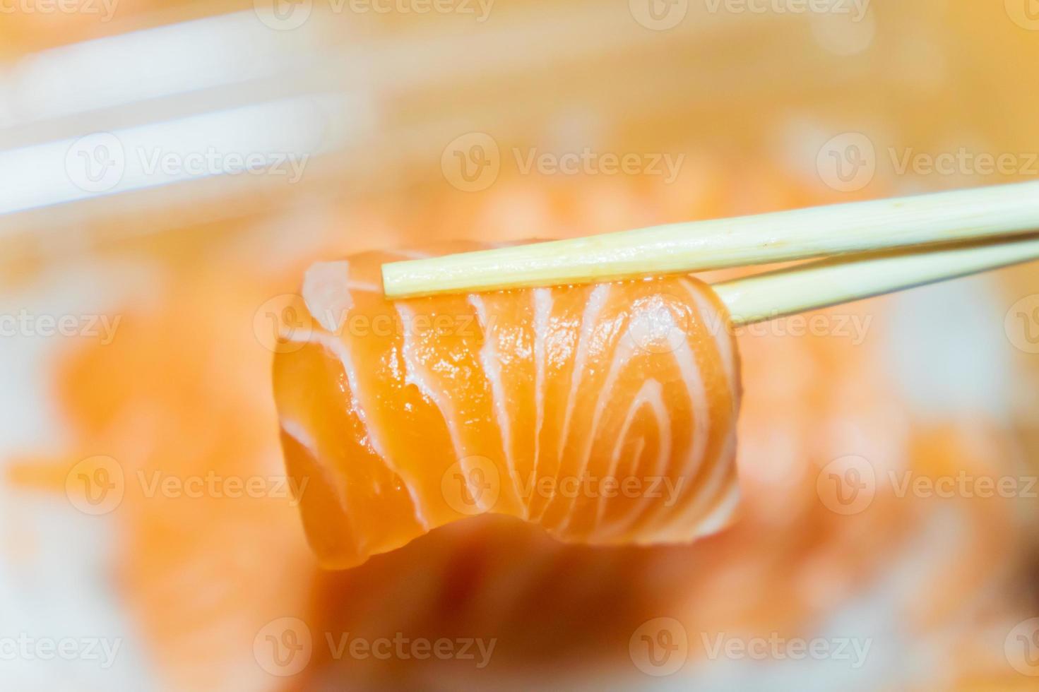 Salmon that has been pinched with chopsticks on a blurred background photo