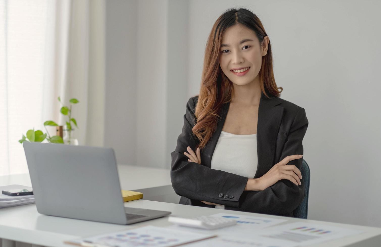 Charming Asian businesswoman working with a laptop at the office. Looking at camera. photo