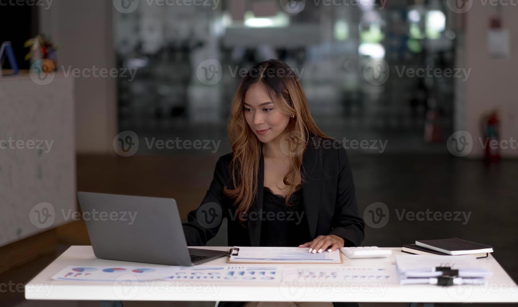 Charming asian businesswoman sitting working on laptop in office. photo