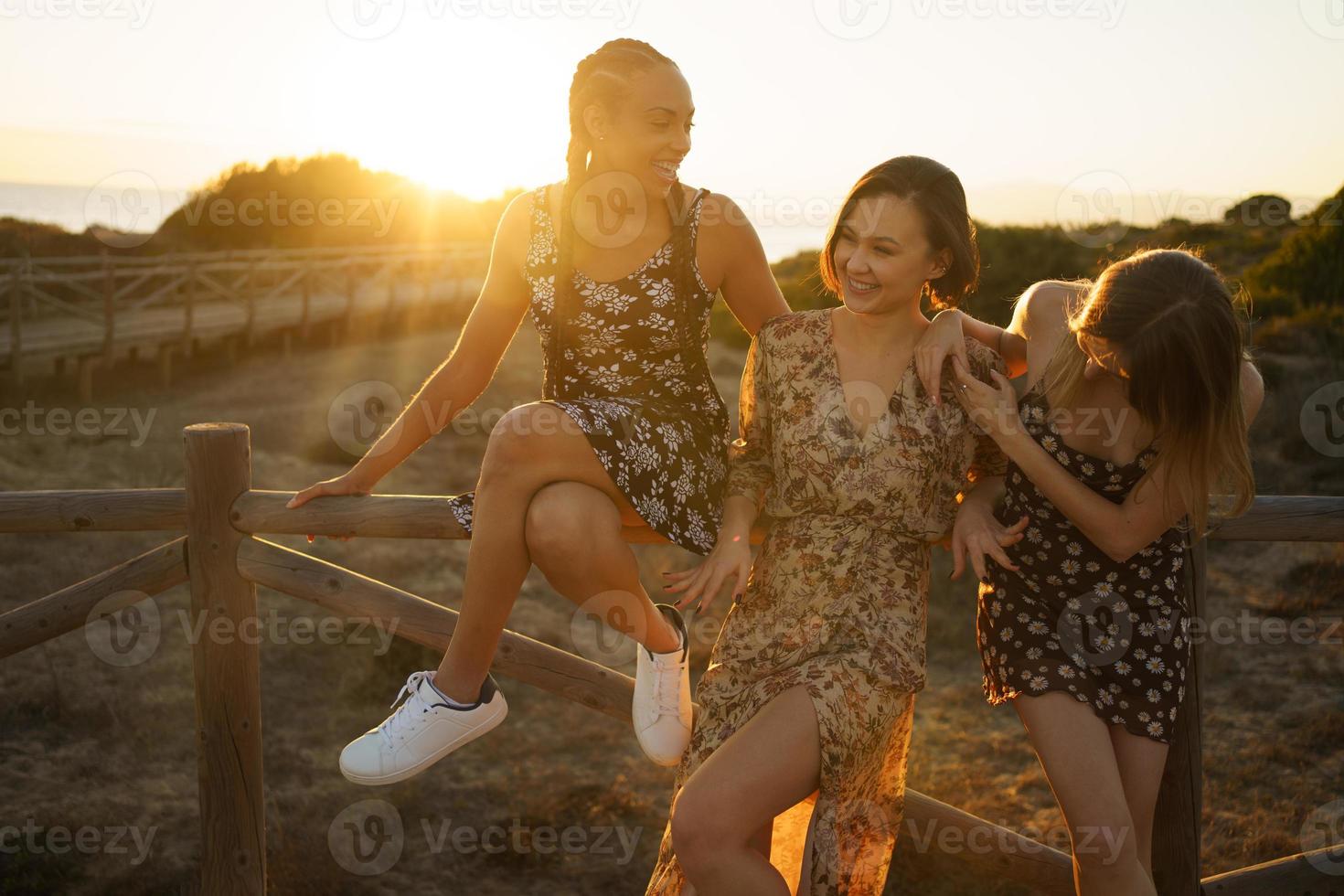 Happy diverse girlfriends near wooden fence photo