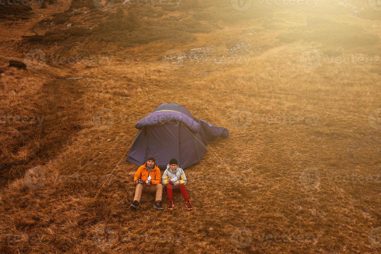 Two tourists sitting near a tent under Mount Hoverla, lunch after a walk. photo