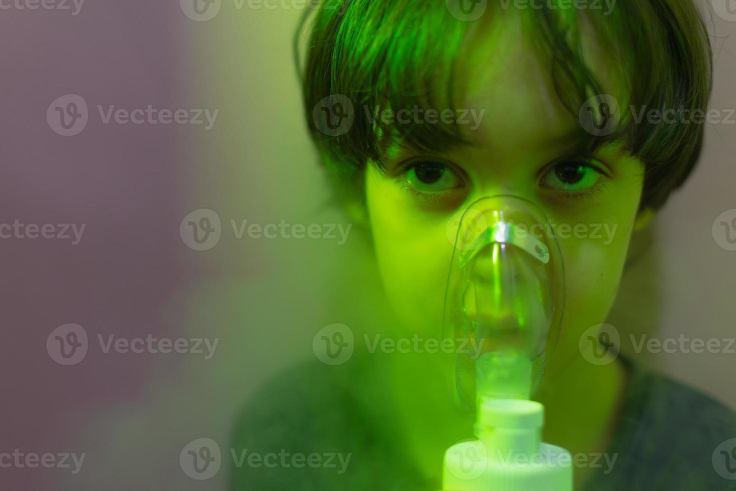 el niño inhala, el niño inhala el medicamento a través de la máscara foto