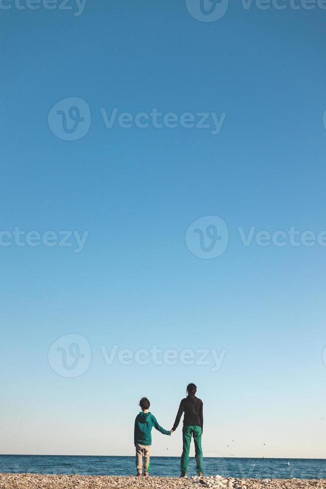 a boy and mother look at the sea photo