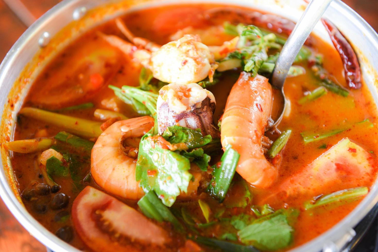 sopa de gambas, sopa picante con camarones, mariscos, leche de coco y ají en una olla, camarones al curry agridulce y calamares comida tailandesa asiática foto