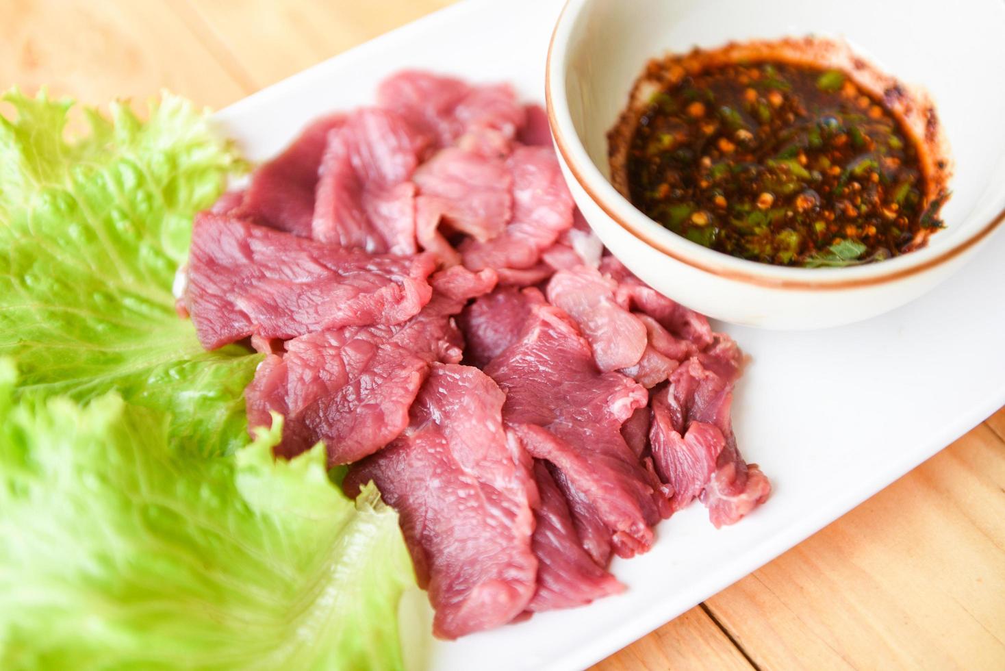 beef meat salad, fresh raw beef slice on plate with spicy sauce and vegetables lettuce - thai food photo