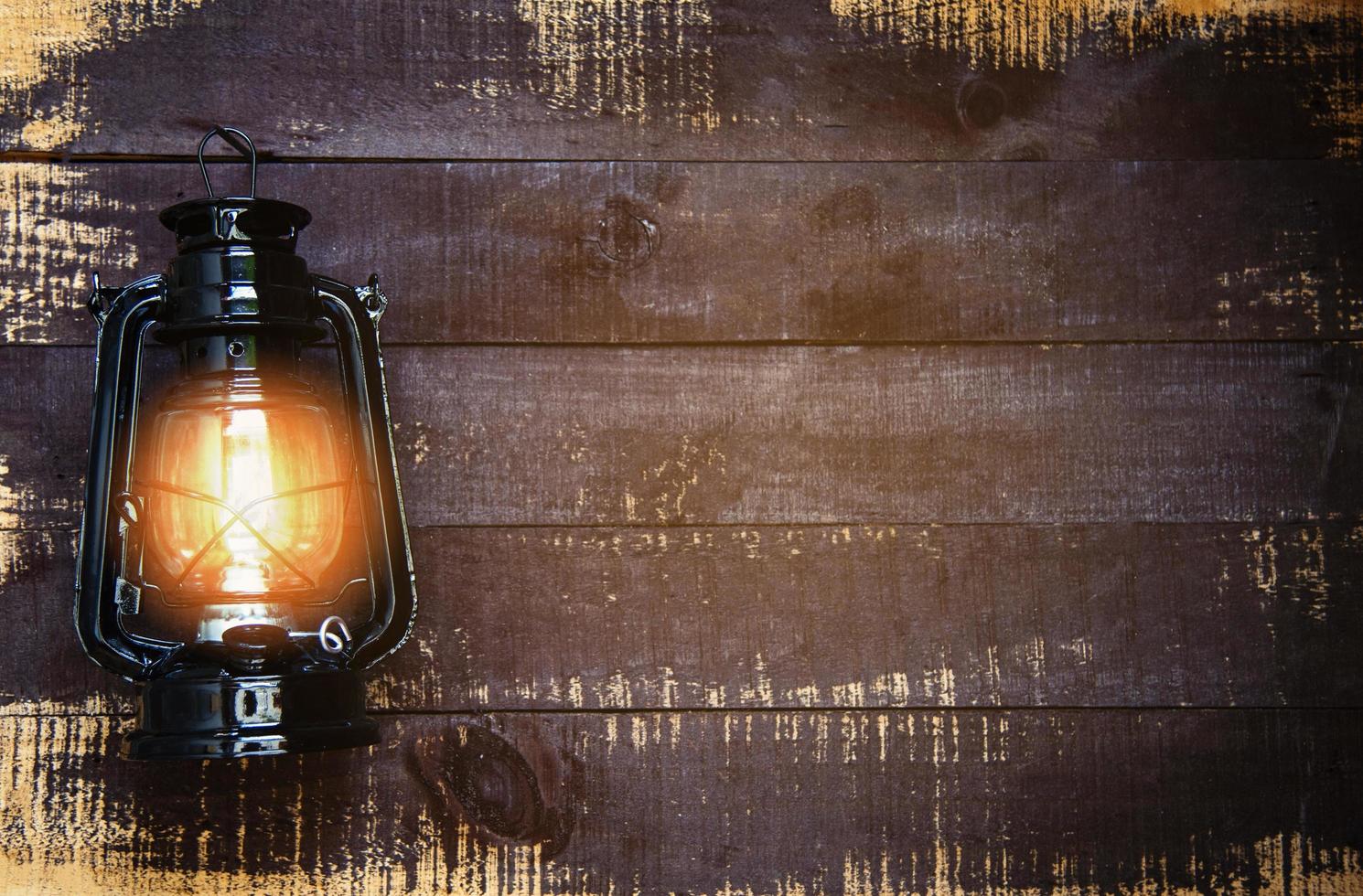 lámpara de aceite por la noche en una pared de madera - farol viejo vintage negro clásico foto