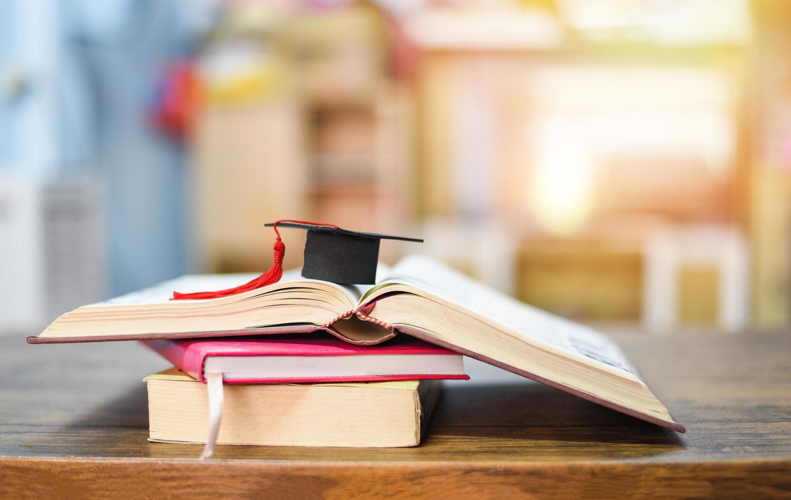 concepto de educación con gorra de graduación en un libro sobre la mesa de madera foto