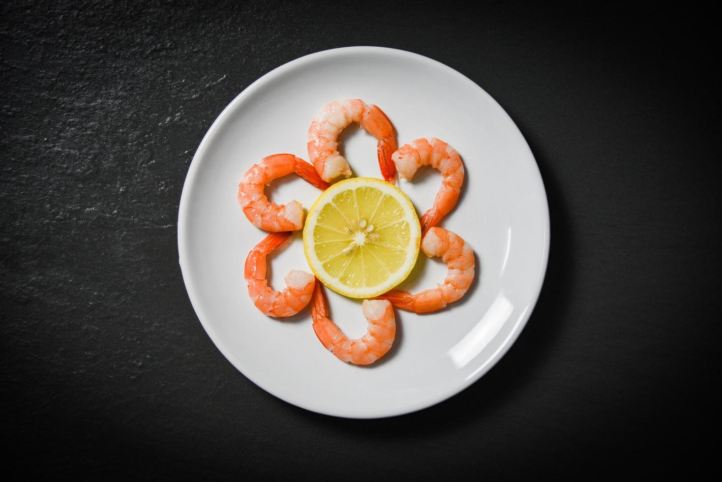 Shrimps prawns served decorate seafood plate and lemon on dark background photo