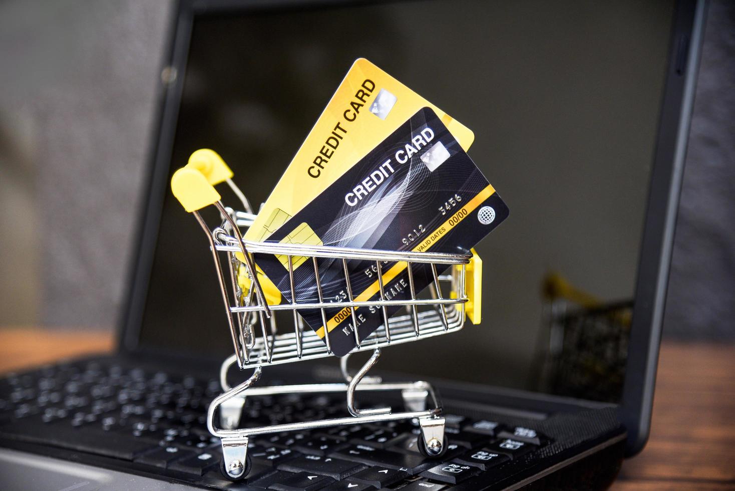 compras en línea con tarjeta de crédito en el carrito de compras en el fondo de la computadora portátil para el pago en línea en el concepto de hogar foto