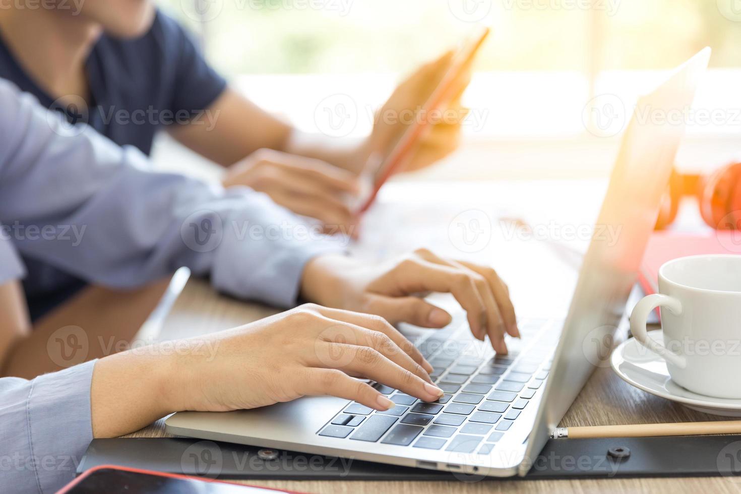 el primer plano de las manos de una mujer está usando una computadora portátil con su novia usando una tableta para trabajar en casa. foto