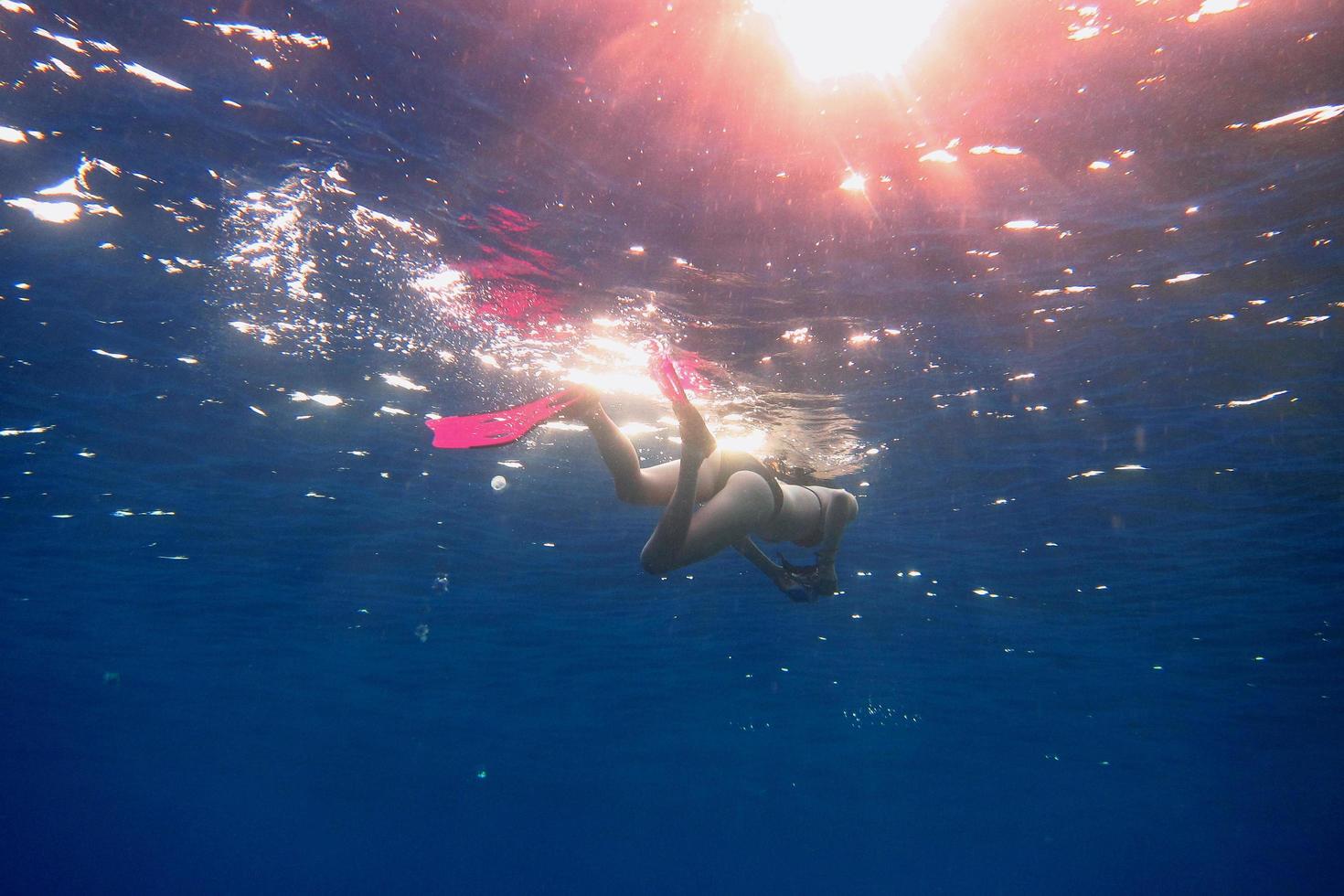 mujer con aletas rosas en el mar azul foto
