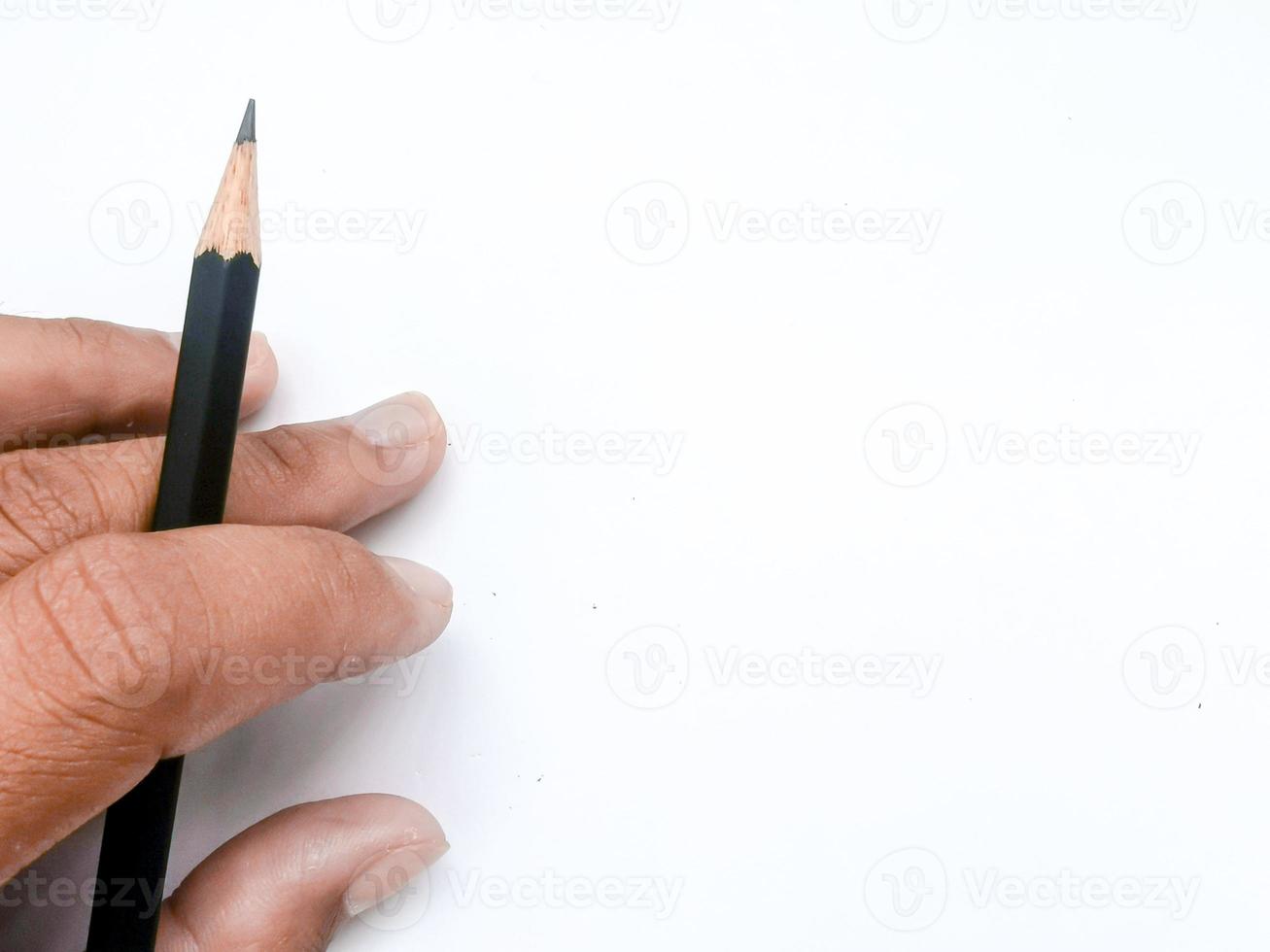 hand holding a black pencil ready to write something on paper photo