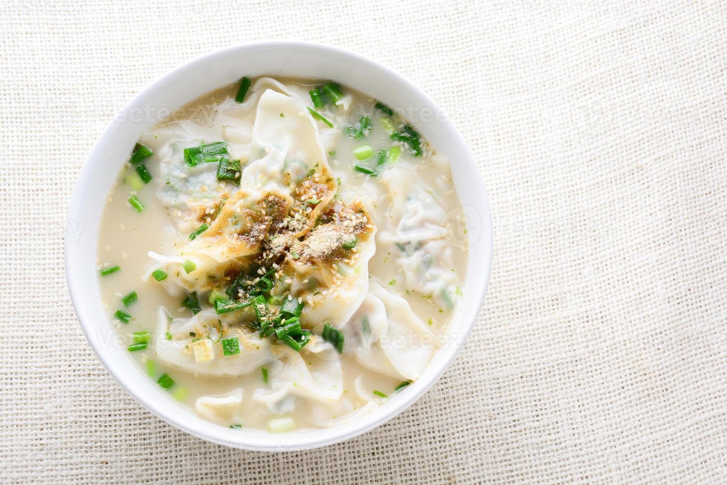 Wonton soup with spring onion served in a white bowl, selective focus photo