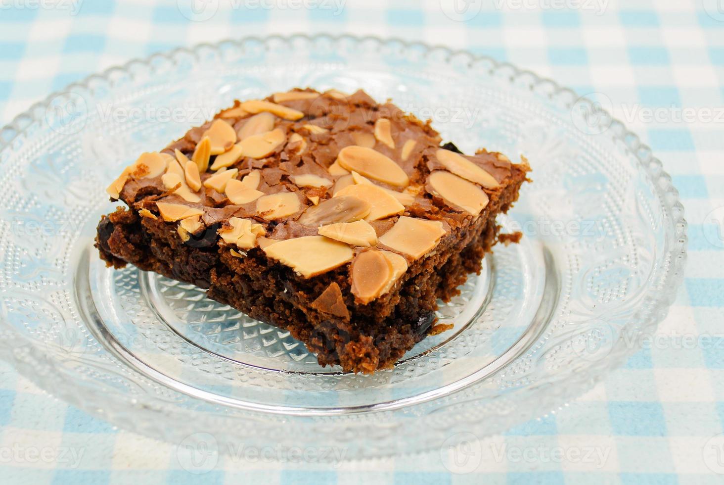 Chocolate brownie with almond topping on glass plated photo