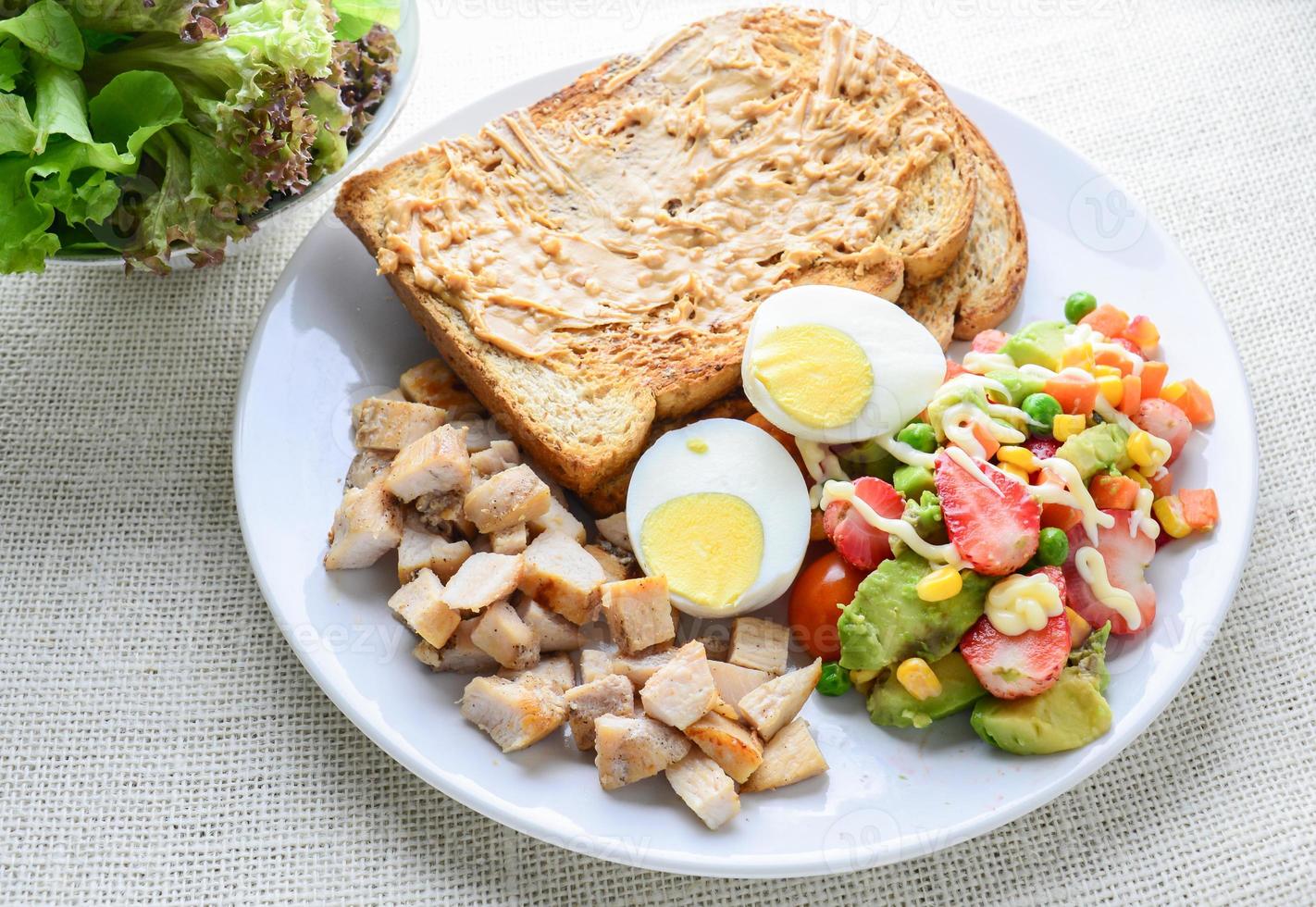 Modern style clean food, Peanut butter with bread, boiled egg, grilled chicken and avocado, strawberry, vegetable salad photo