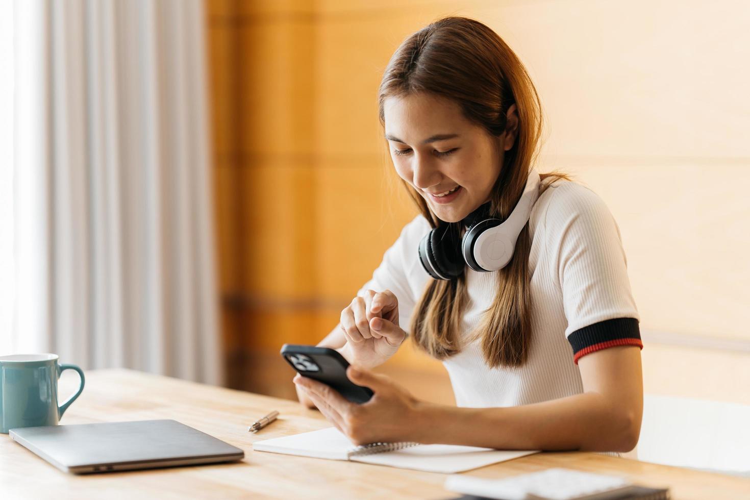 Happy asian businesswoman wearing headset make notes talk by conference call doing video chat on laptop in office, smiling chinese support service agent write information consult customer photo