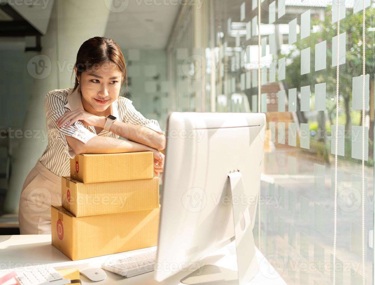 Portrait young attractive asia female owner startup business  work happy with box at home prepare parcel delivery in sme supply chain, procurement, omnichannel commerce online concept. photo