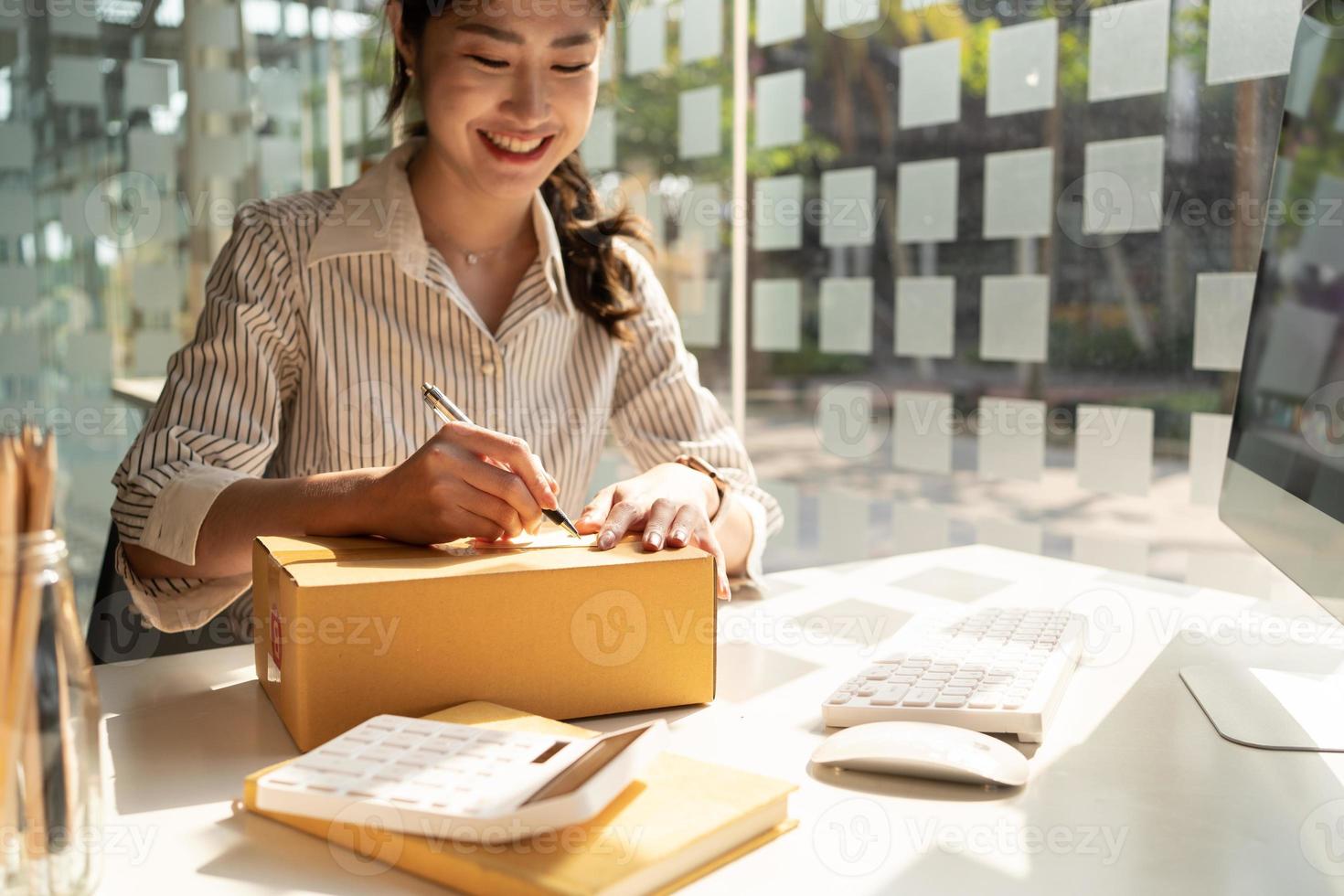 Starting small businesses SME owners female entrepreneurs Write the address on receipt box and check online orders to prepare to pack the boxes, sell to customers, sme business ideas online. photo