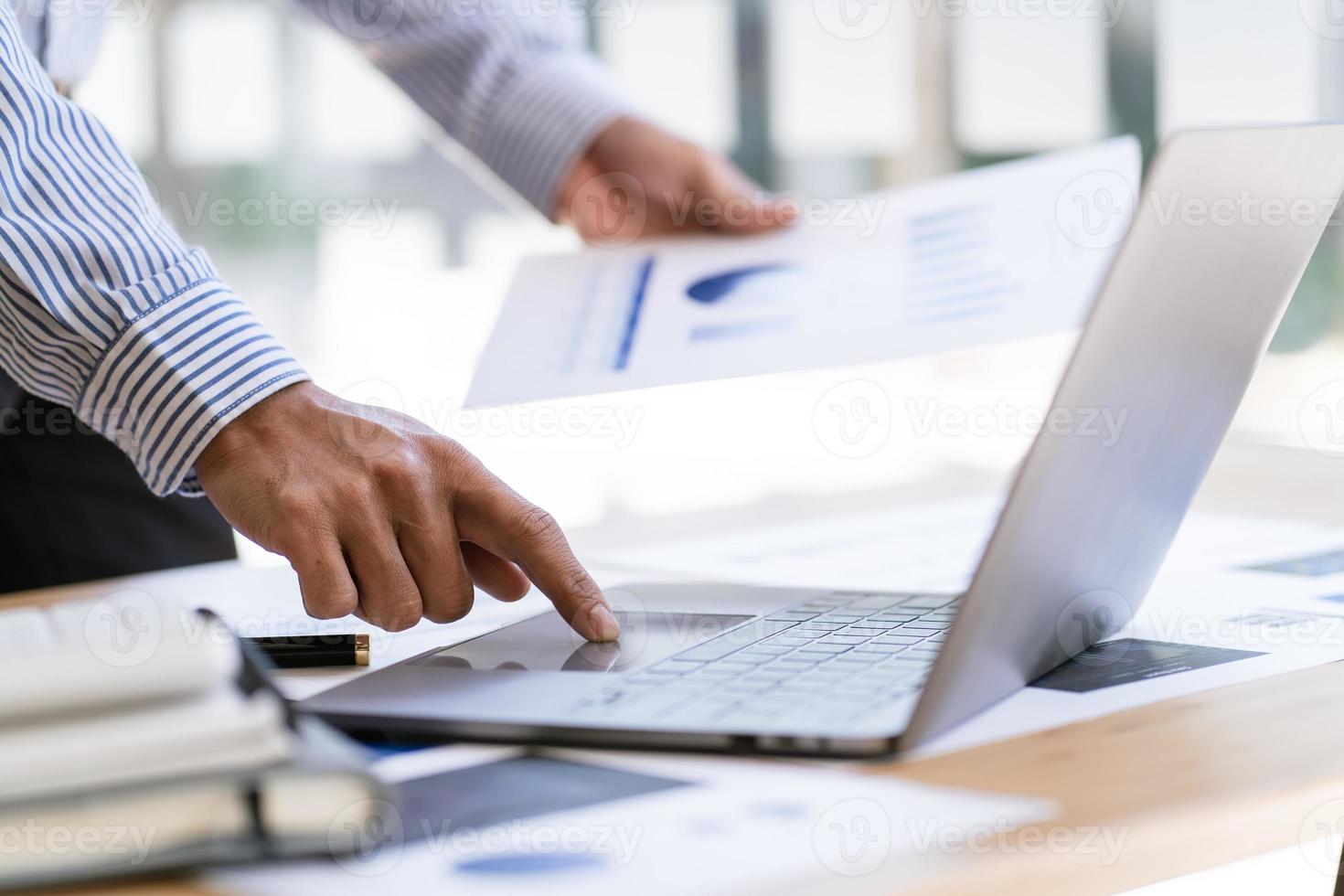 Manager is using a laptop computer while analyzing the company's financial statements on the screen. photo