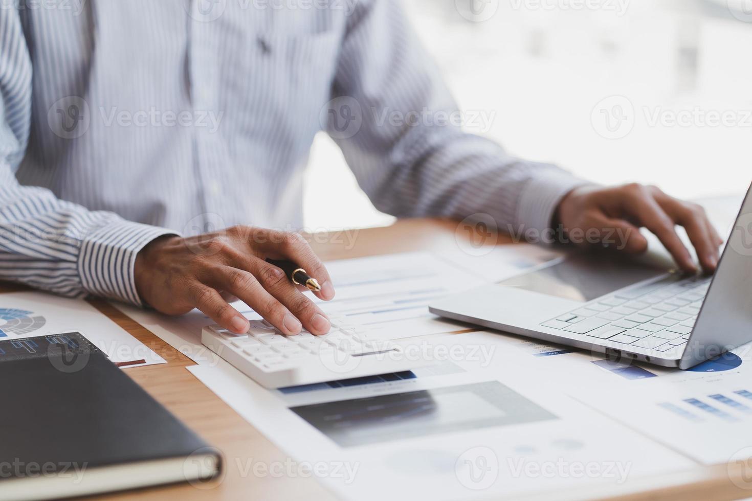 Businessman or accountant working on calculator to calculate business data concept. Accounting,investment advisor consulting situation on the financial report and planning a marketing plan at office.. photo