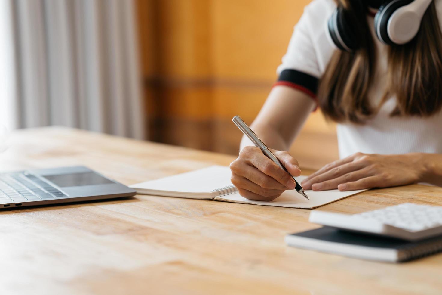 los hombres de negocios usan teléfonos móviles y toman notas en sus cuadernos mientras trabajan en computadoras portátiles, negocios en línea, trabajo desde casa, concepto de teletrabajo. foto