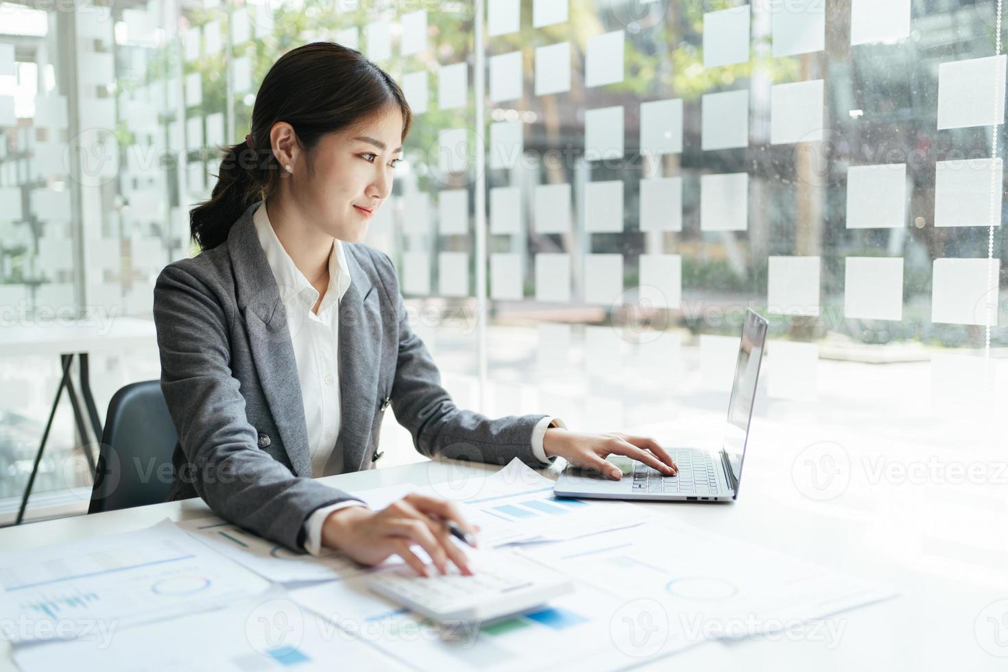 asian accountant woman working about financial with business report and calculator.financial or accounting concept. photo