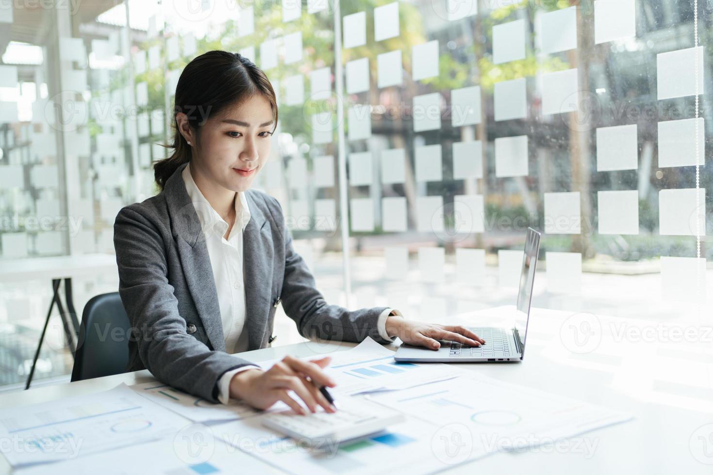 asian accountant woman working about financial with business report and calculator.financial or accounting concept. photo