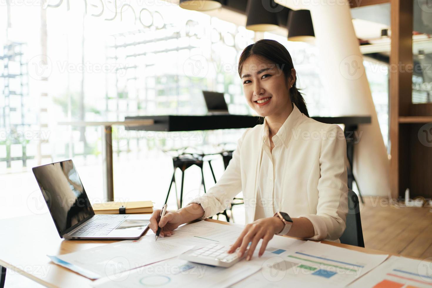 Portrait of Asian young female working on laptop and financial report at office. photo