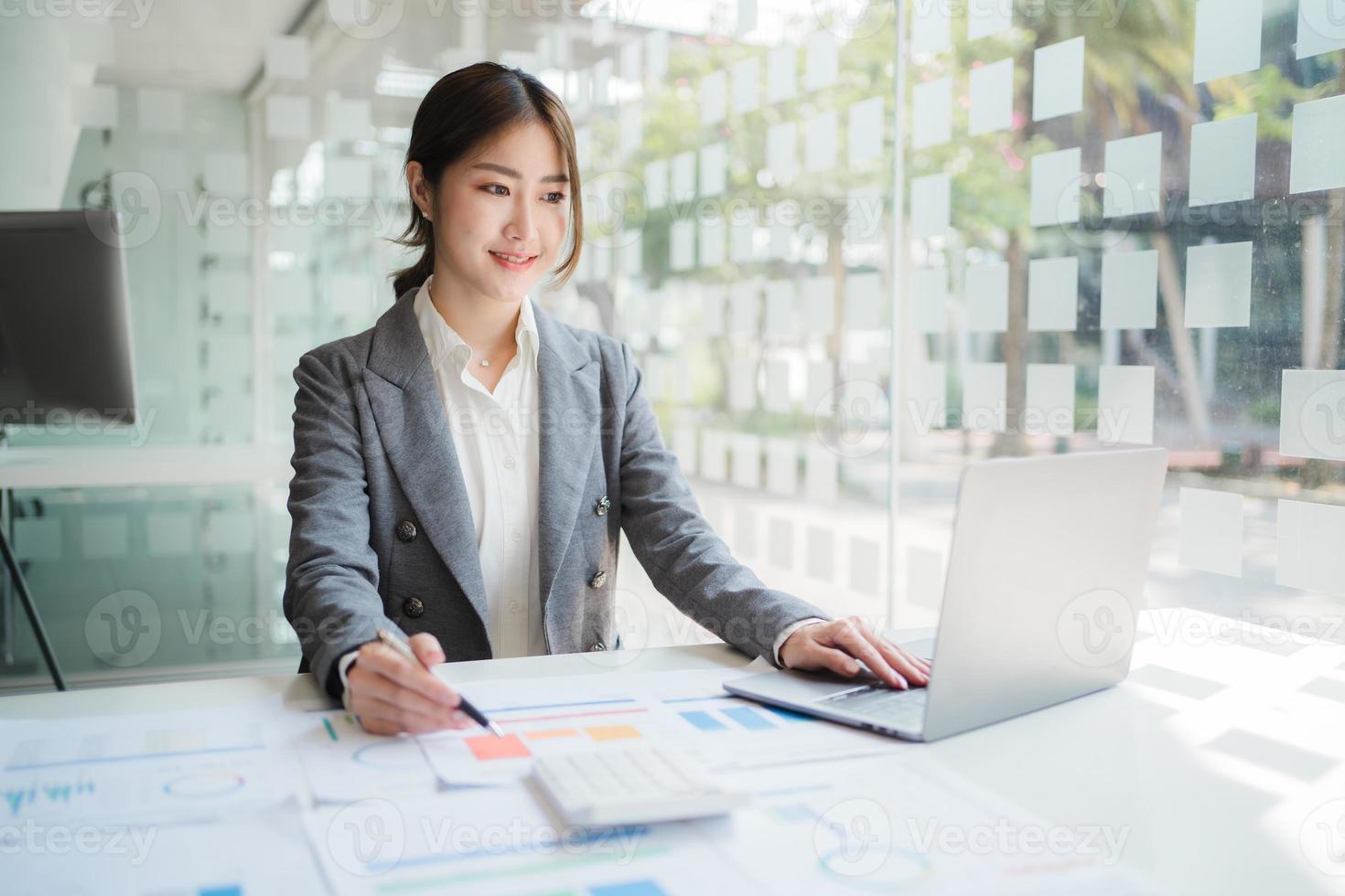 Asian woman working in the office using a laptop. photo