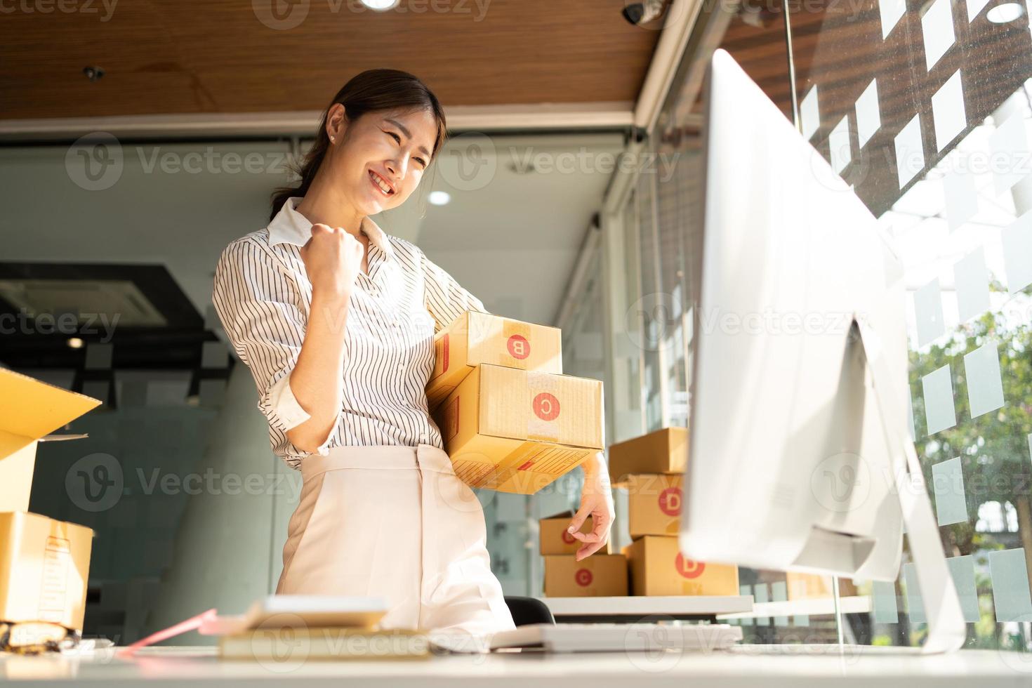 Portrait young attractive asia female owner startup business  work happy with box at home prepare parcel delivery in sme supply chain, procurement, omnichannel commerce online concept. photo