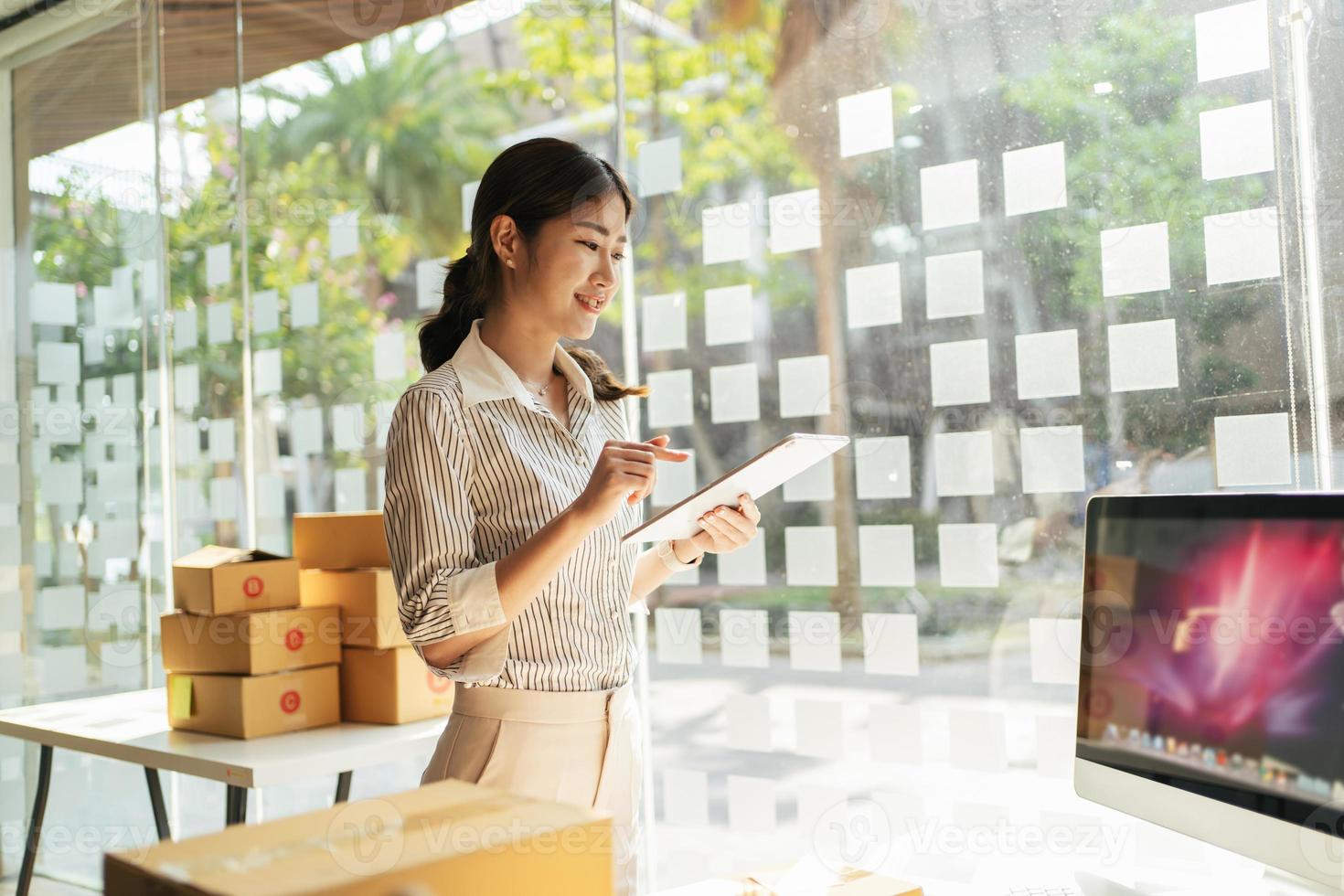 Portrait young attractive asia female owner startup business look at camera work happy with box at home prepare parcel delivery in sme supply chain, procurement, omnichannel commerce online concept. photo