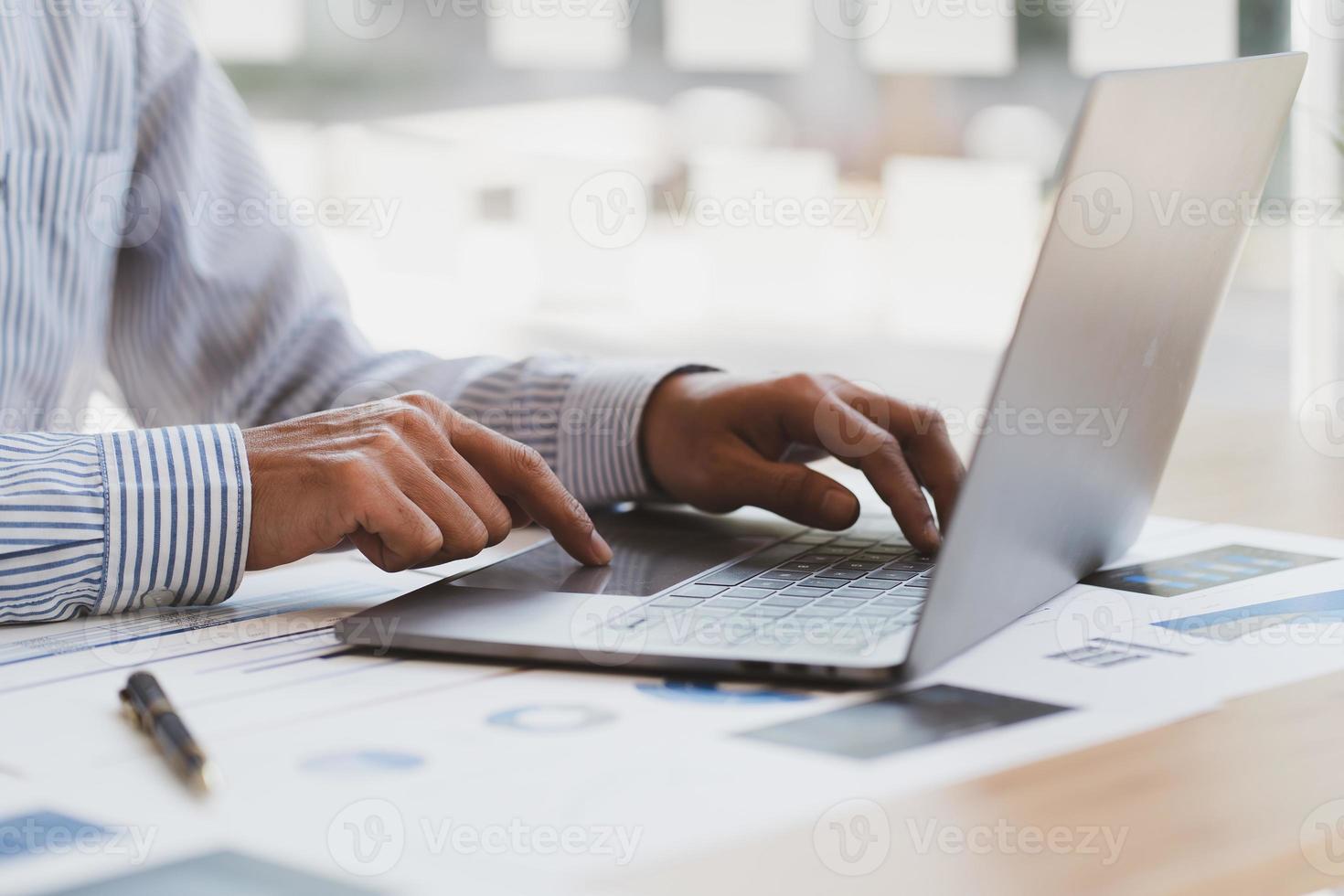 Manager is using a laptop computer while analyzing the company's financial statements on the screen. photo