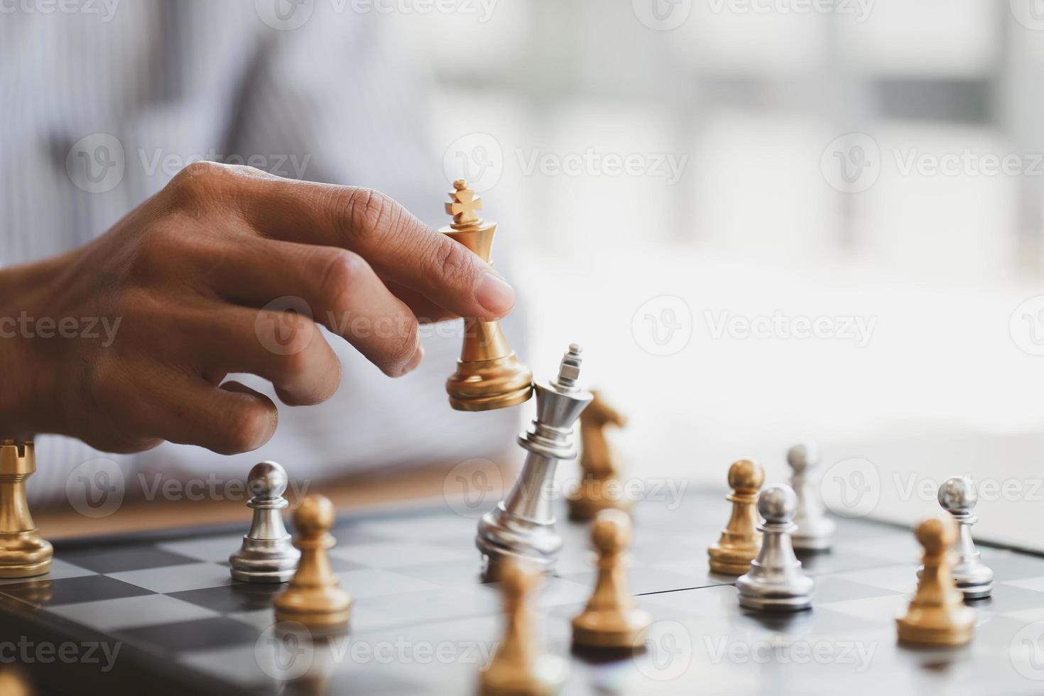 mano de hombre de negocios moviendo la figura del rey del ajedrez dorado y el oponente de jaque mate durante la competencia de tablero de ajedrez. concepto de estrategia, éxito, gestión, planificación empresarial, disrupción y liderazgo foto