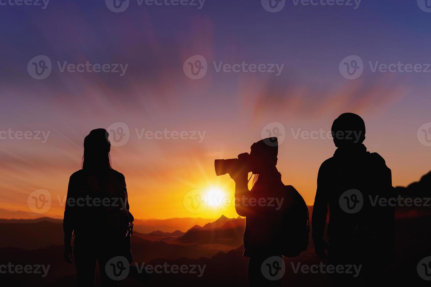 Young woman photographer taking photo her friend with sunset on mountain natural background.