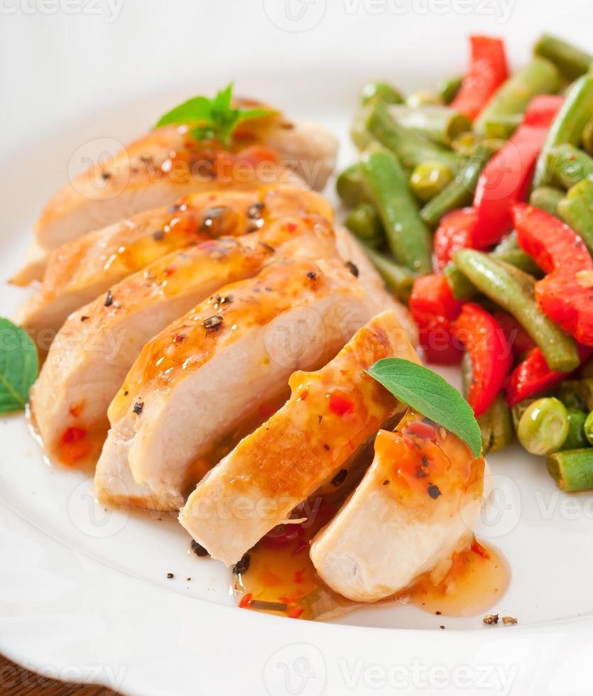 Chicken breast with vegetables and sauce decorated with basil leaves