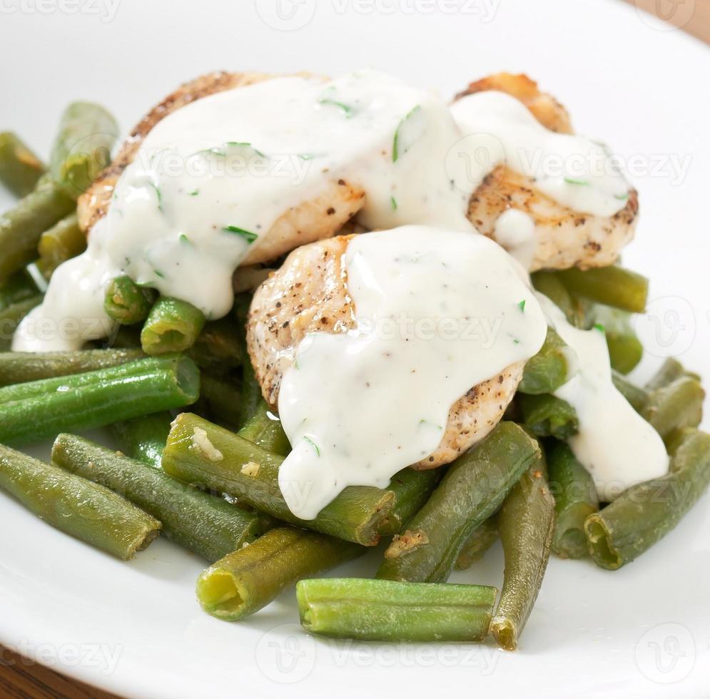 pechuga de pollo a la plancha con judías verdes y salsa en un plato blanco. foto