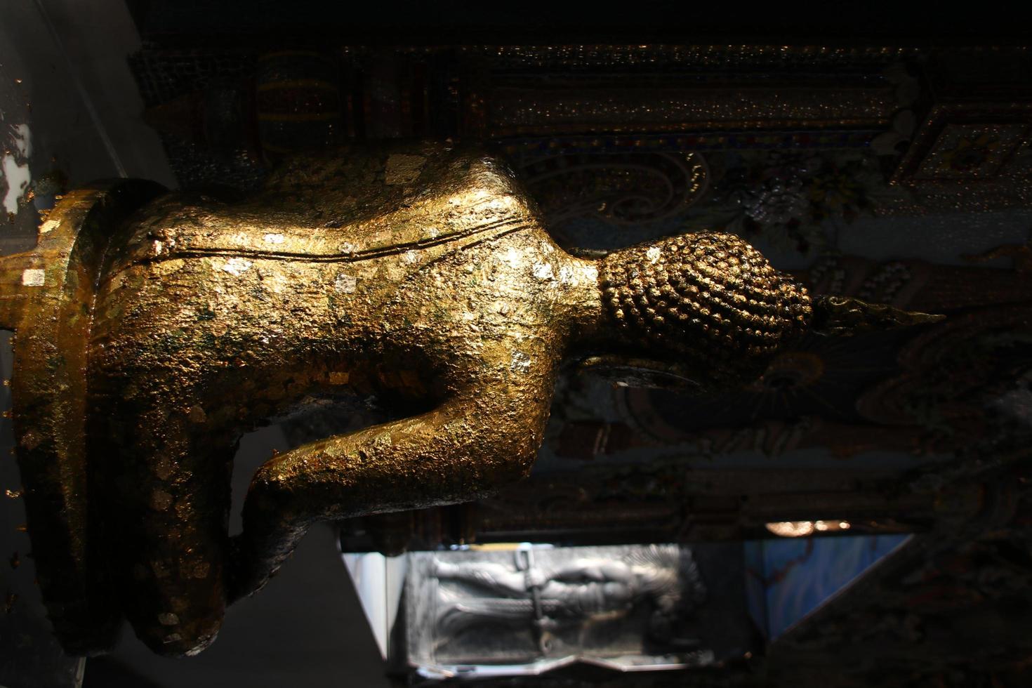 la parte posterior de la antigua estatua de buda está al lado de la ventana de la iglesia, el cuerpo de la cubierta de la placa de oro de la estatua de buda, tailandia. foto