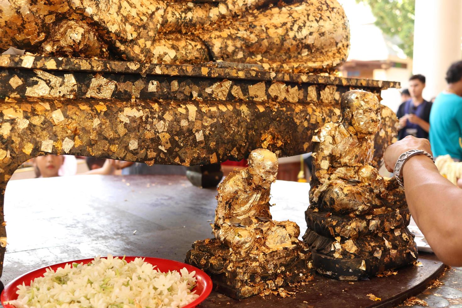 Hand is covering with gold leaf the native statue of monk, Thailand photo