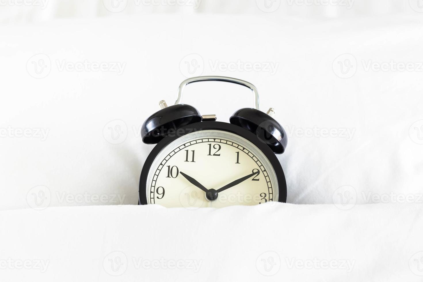 Alarm clock in white blanket photo