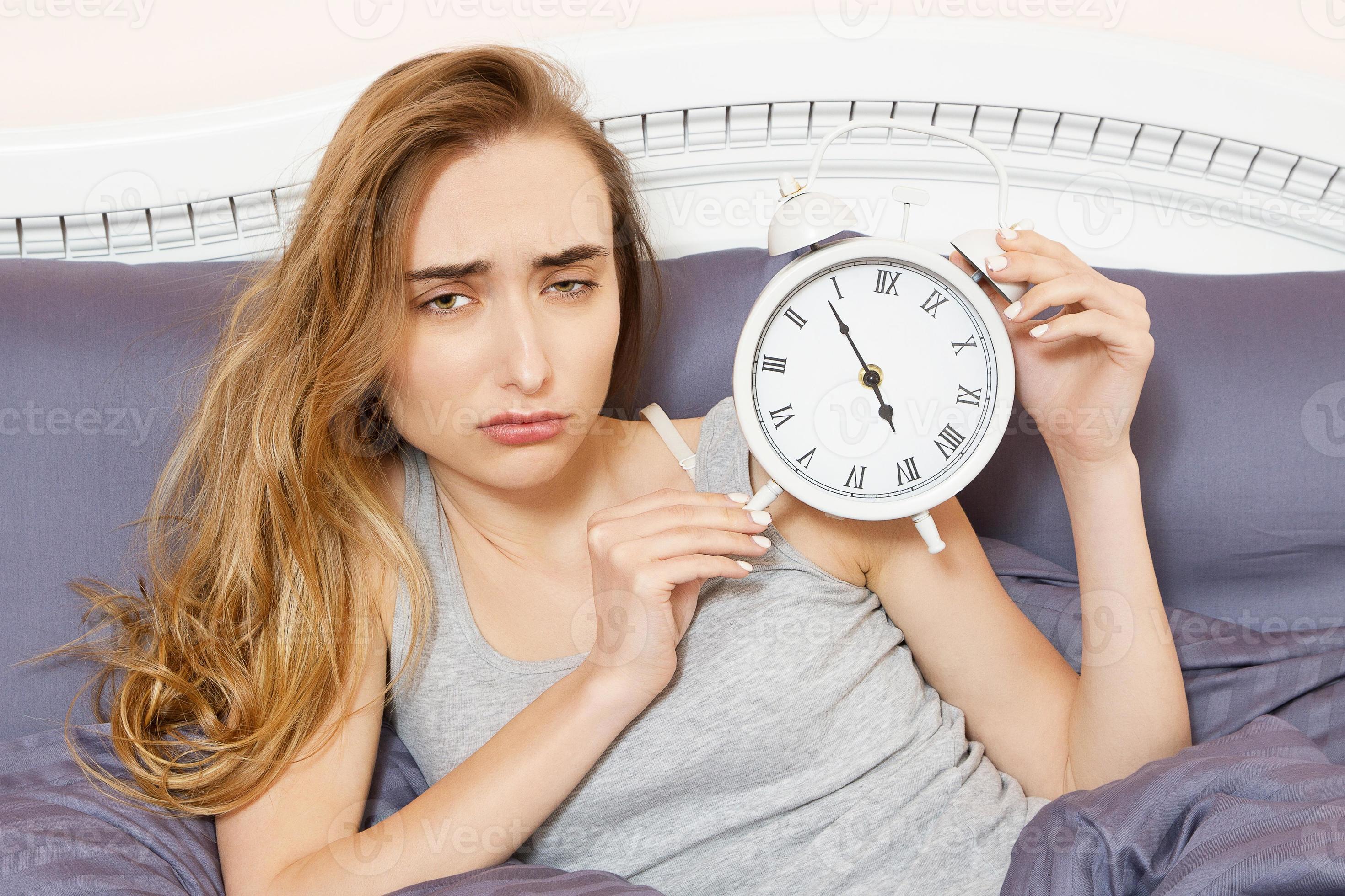 Shocked young woman waking up with alarm, overslept work, bad sleep