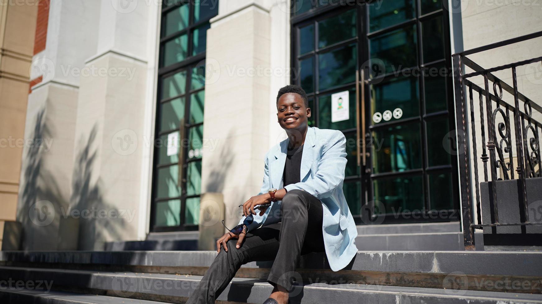 hombre afroamericano divirtiéndose caminando en el centro de la ciudad - joven feliz disfrutando del tiempo una puesta de sol al aire libre - estilo de vida de generación milenaria y concepto de actitud positiva de la gente foto