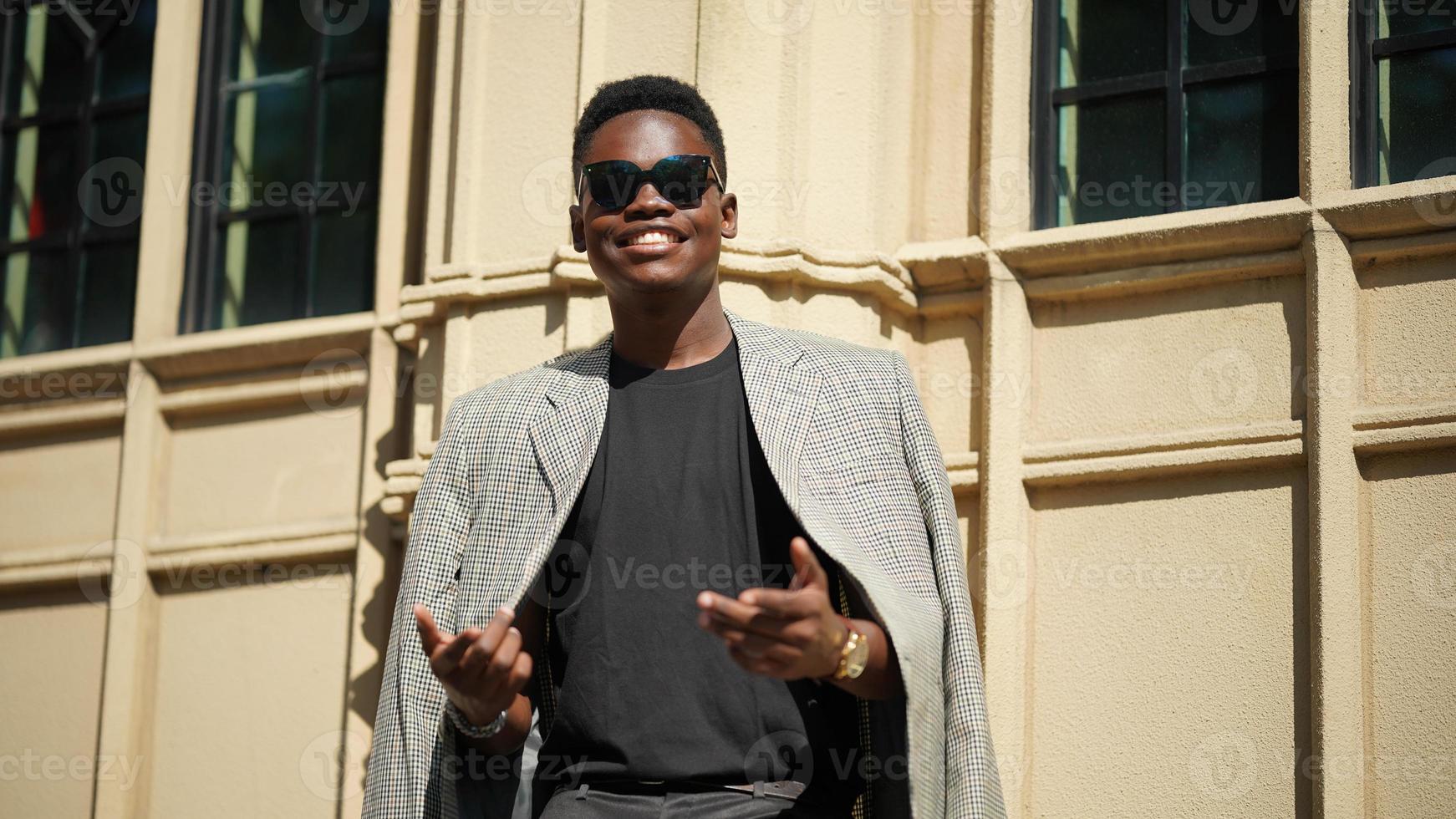 hombre afroamericano divirtiéndose caminando en el centro de la ciudad - joven feliz disfrutando del tiempo una puesta de sol al aire libre - estilo de vida de generación milenaria y concepto de actitud positiva de la gente foto