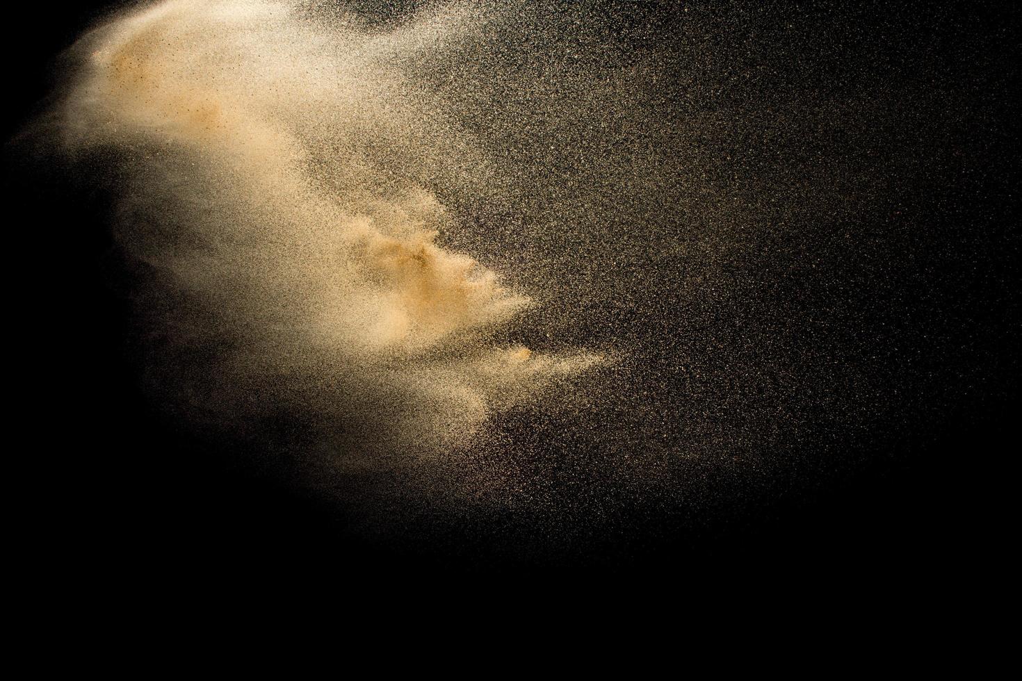 Abstract sand cloud.Golden colored sand splash agianst dark background.Yellow sand fly wave in the air. Sand explode on black background ,throwing freeze stop motion concept. photo