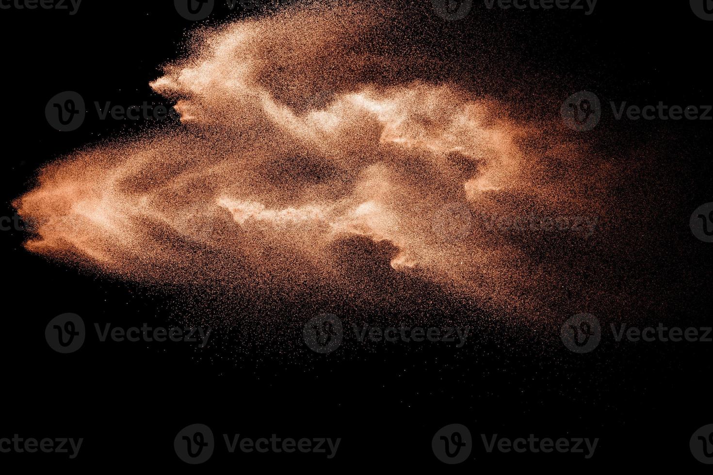 Brown colored sand splash against dark background. Dry river sand explosion isolated on black background. Abstract sand cloud. photo