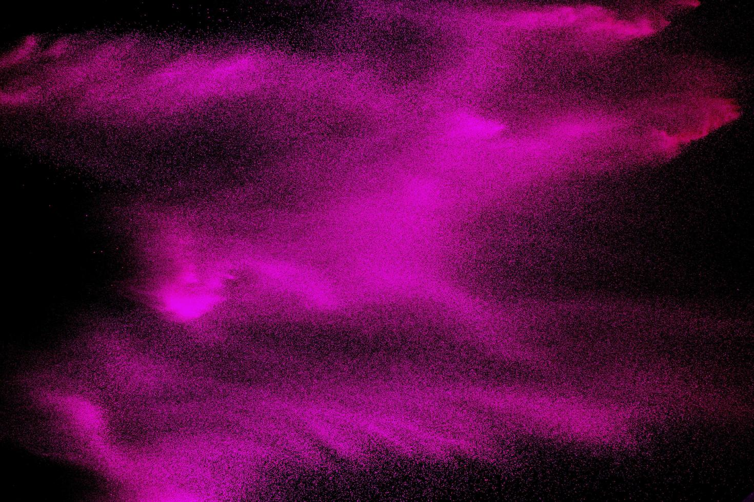 Pink particle dust splash on black background. Pink powder exploding. photo