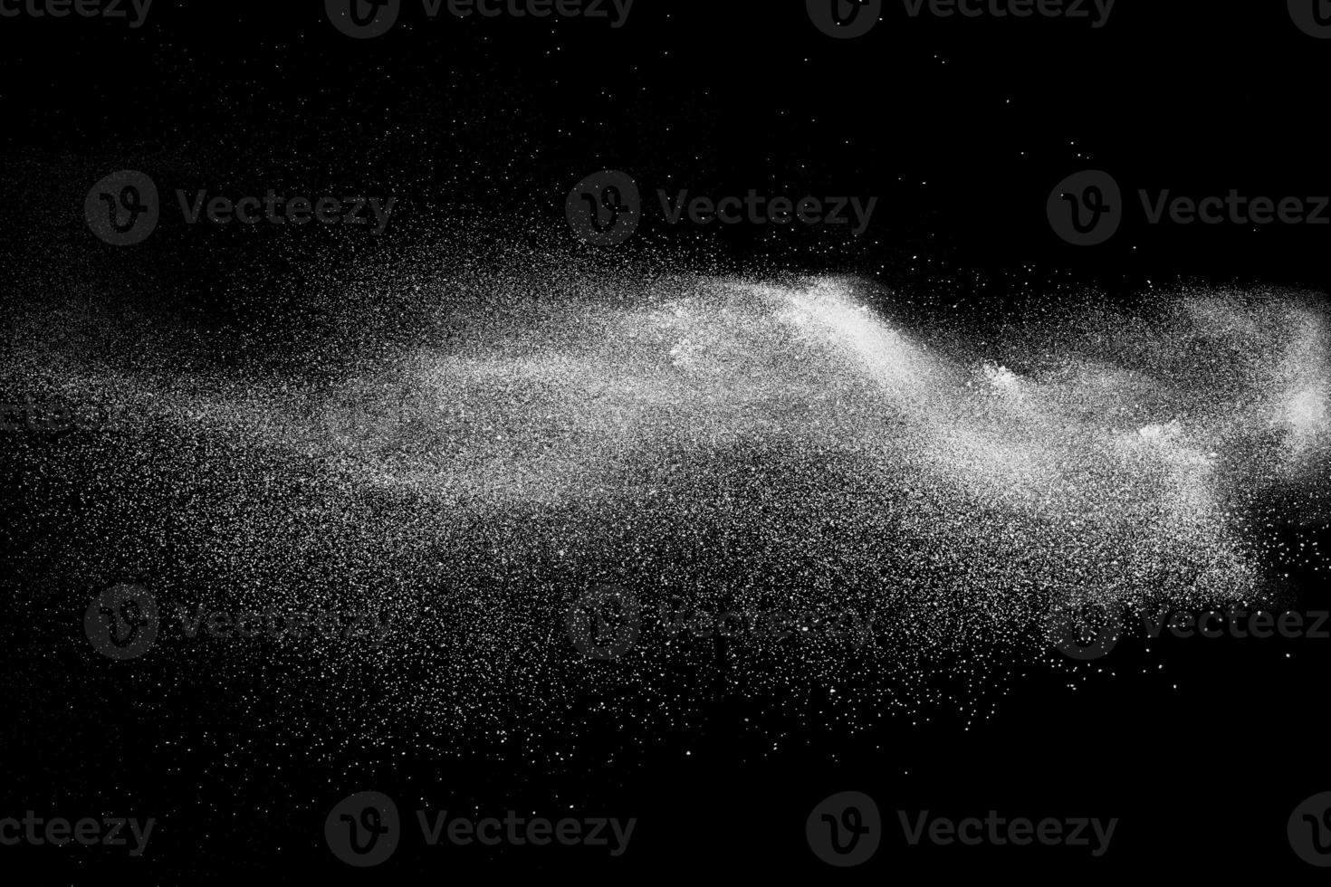 Freeze motion of white dust particles on black background. White powder explosion. photo