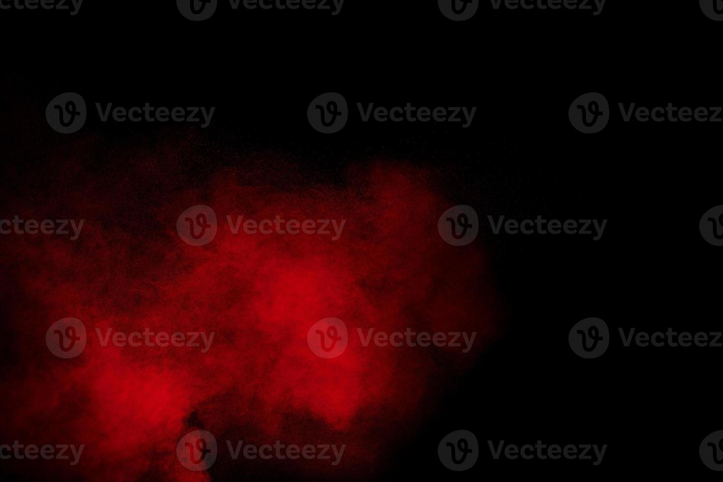 Red powder explosion cloud on black background. Freeze motion of red color dust  particles splashing. photo