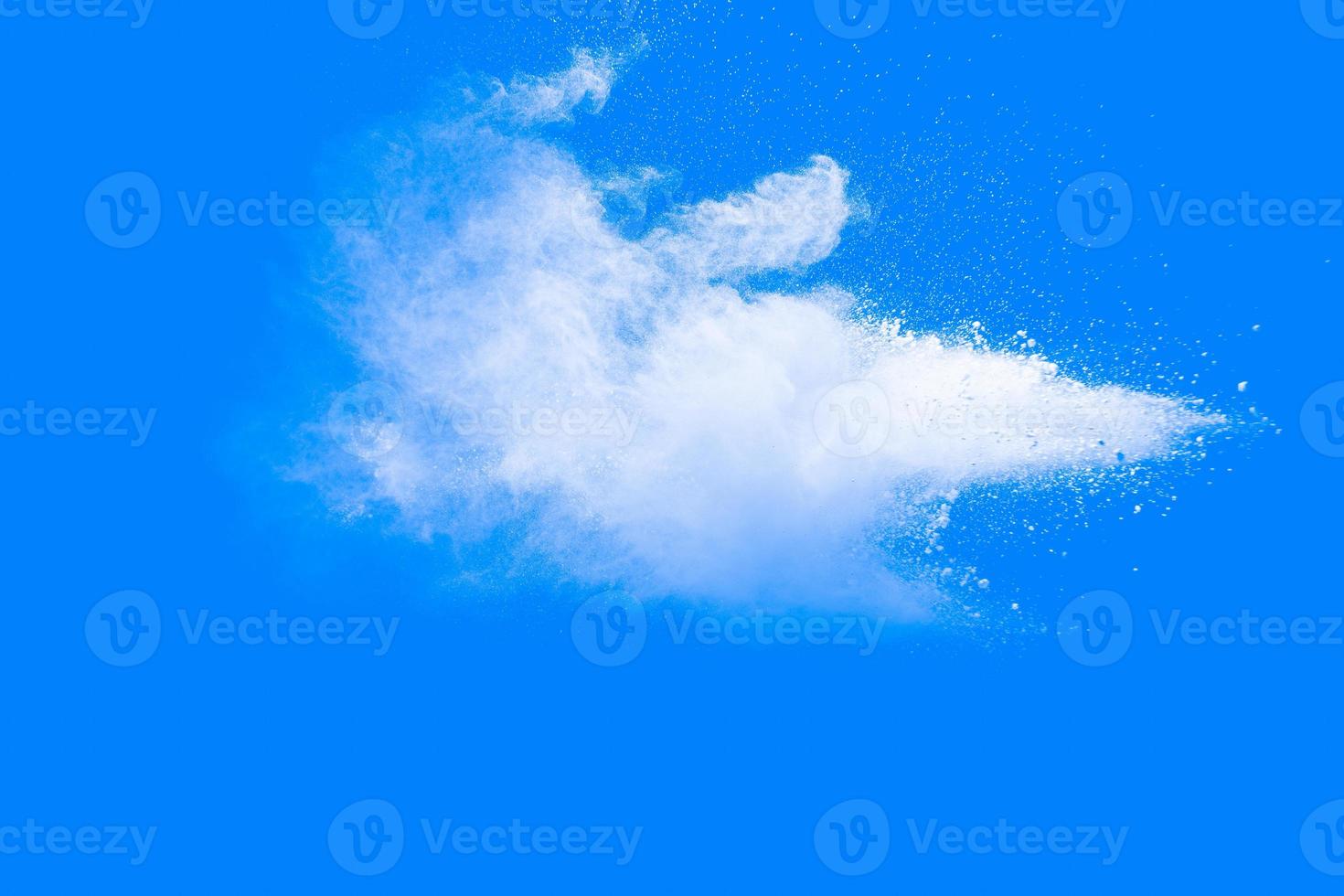 White powder explosion isolated on blue background. White dust particles splash.Color Holi Festival. photo