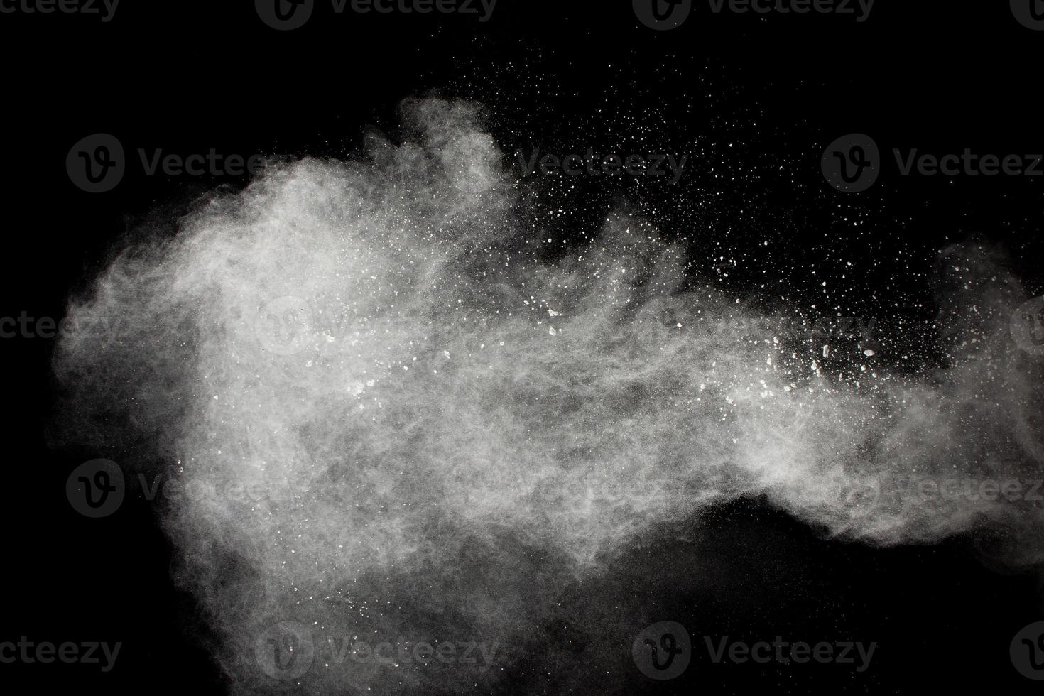 Freeze motion of white dust particles splash on black background. photo